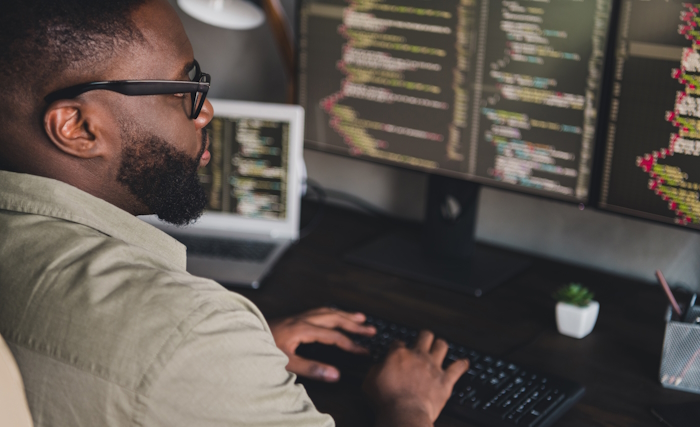 a man working at a computer with multiple monitors